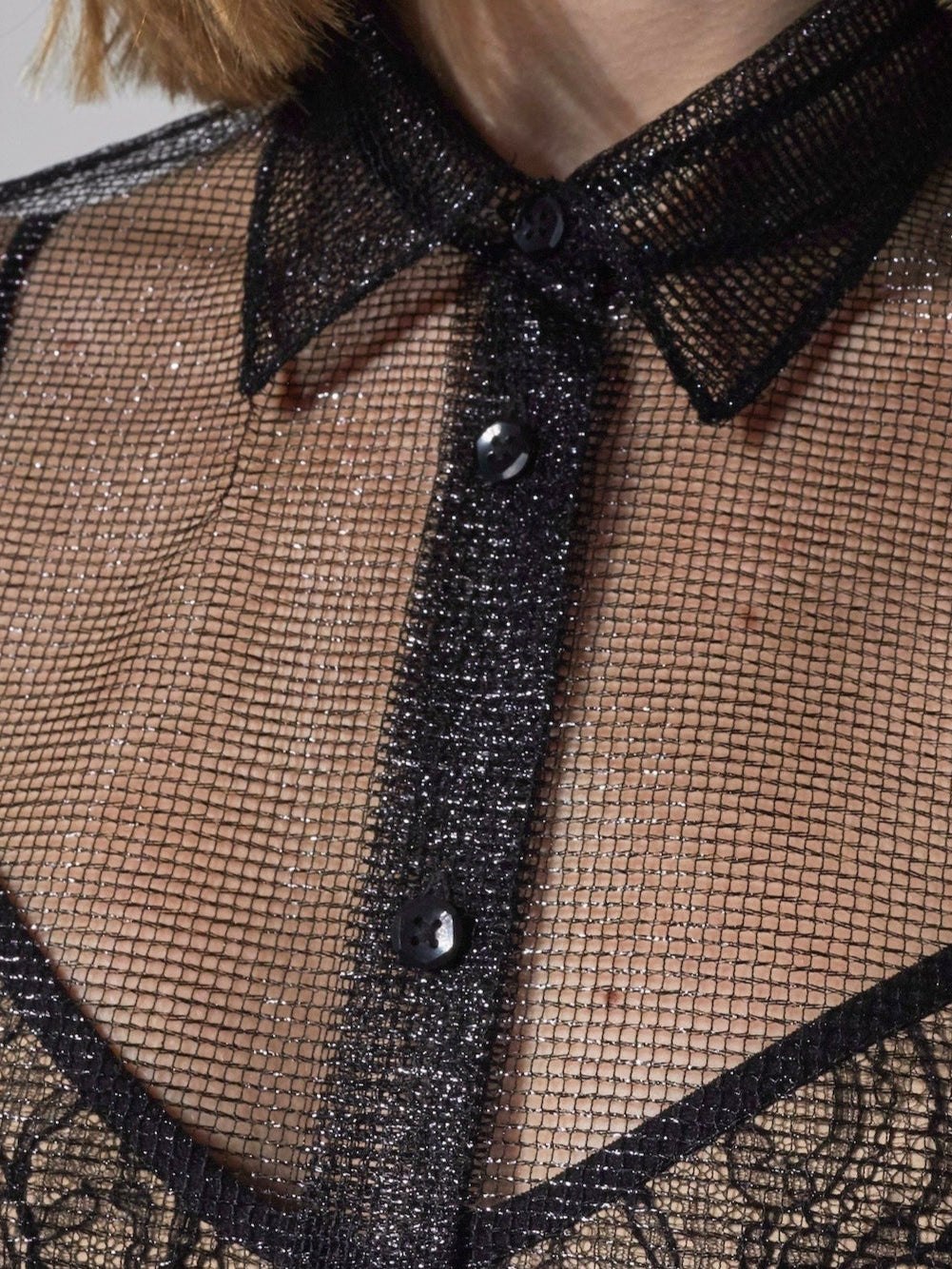Close view of the black metallic mesh, collar and button front of CHUCHOTER